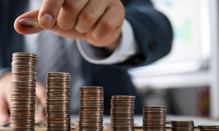 Male hands in suit stack coins on table