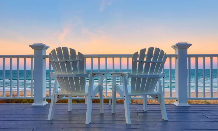 Chair sits on the balcony deck of a house looking out over the beach and the ocean