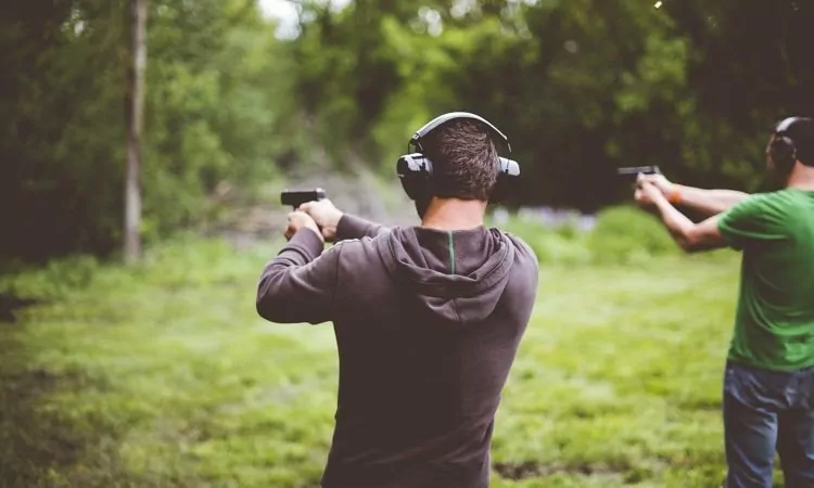 Shallow focus shot of people shotting guns in nature