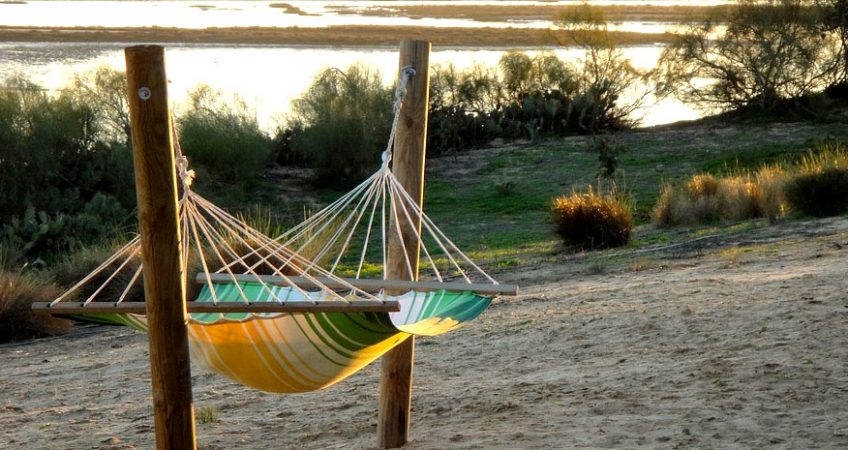 A striped hammock in the shade overlooks the ocean