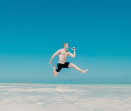 a man in a bathing suit jumping very high against a blue background