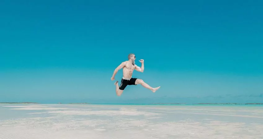 a man in a bathing suit jumping very high against a blue background