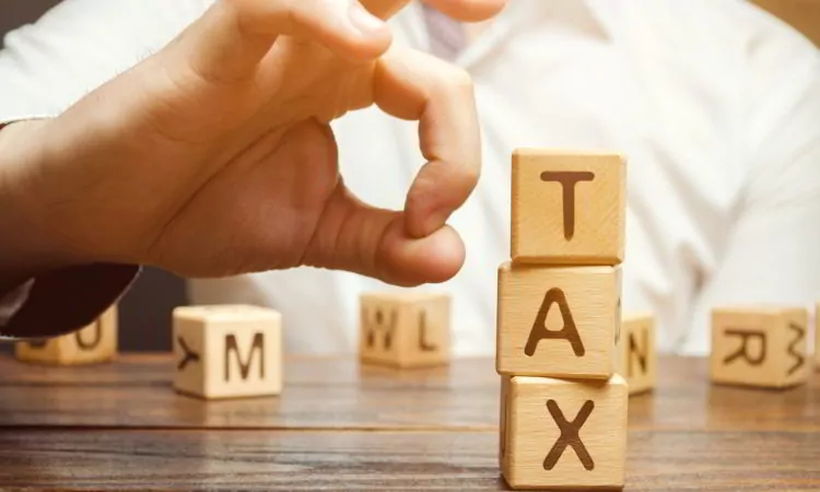 Businessman removes wooden blocks with the word Tax