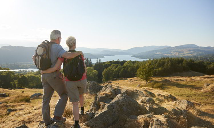 Senior couple standing at top of hill on hike through countryside