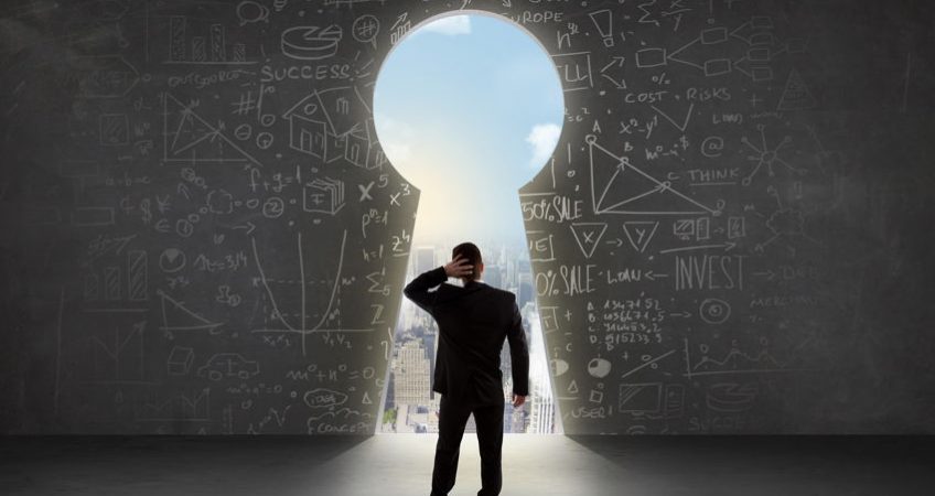 A businessman looking through a giant keyhole