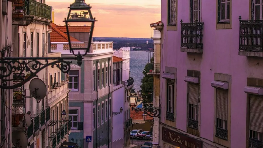 lisbon at sunset. view of colonial buildings on either side of the street down to the river at the bottom of the hill