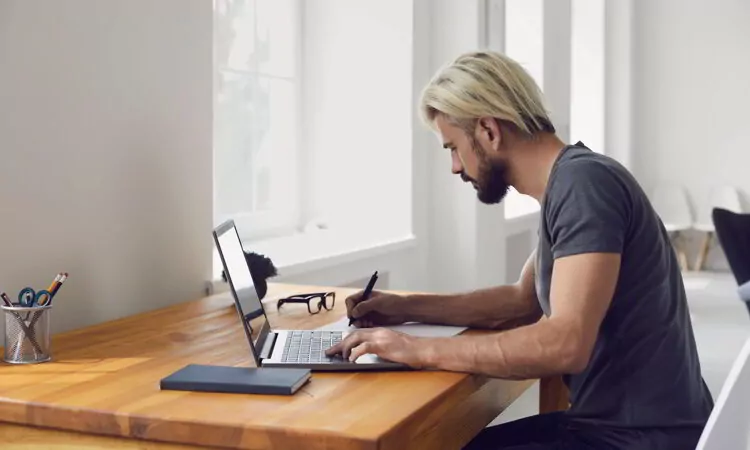 Young guy writing down main points from online business conference