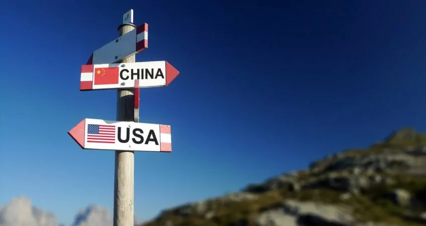 USA and Chinese flags on mountain signpost