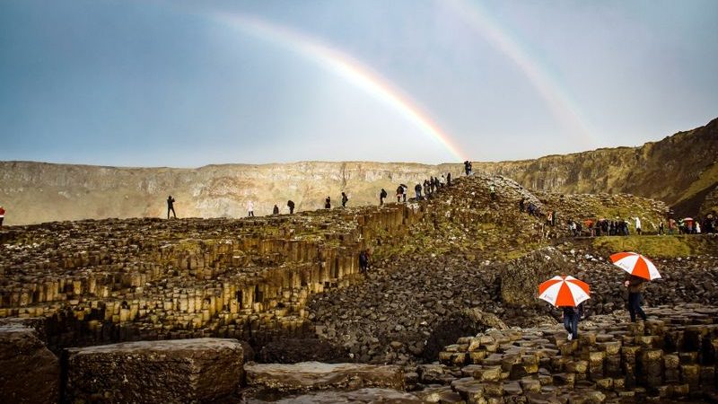 people at giants causeway and rainbows