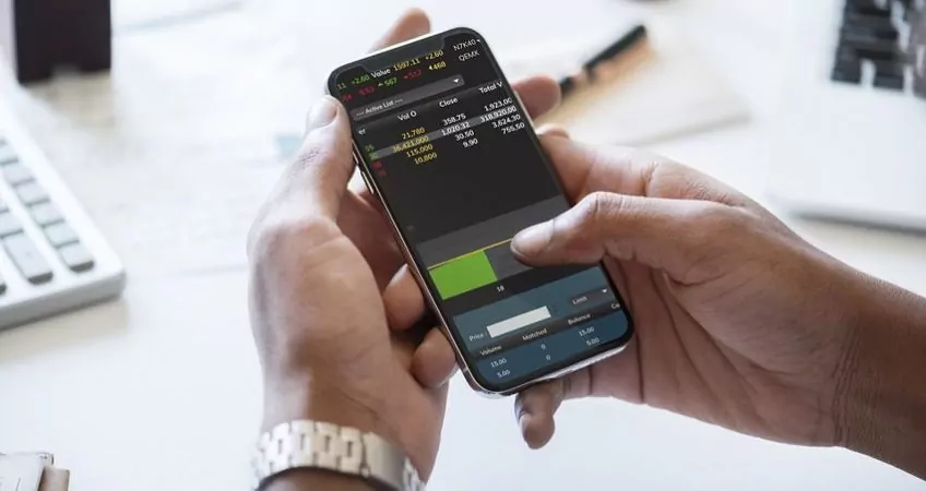 hands of a man holding a smartphone and looking at stocks