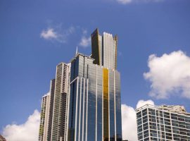 A view from below of the top of a bank glass building, blue skys in the background