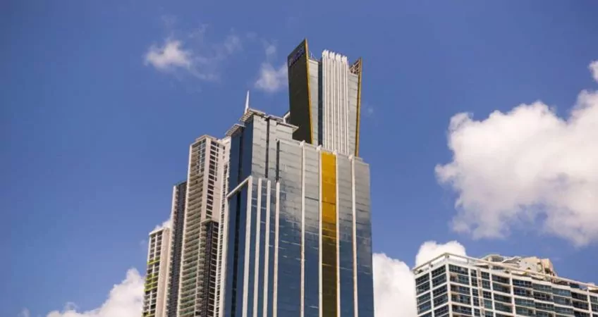 A view from below of the top of a bank glass building, blue skys in the background