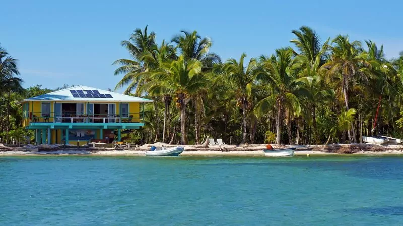 Caribbean property, a colorful house in the beachfront with clear water, white sand and palm trees