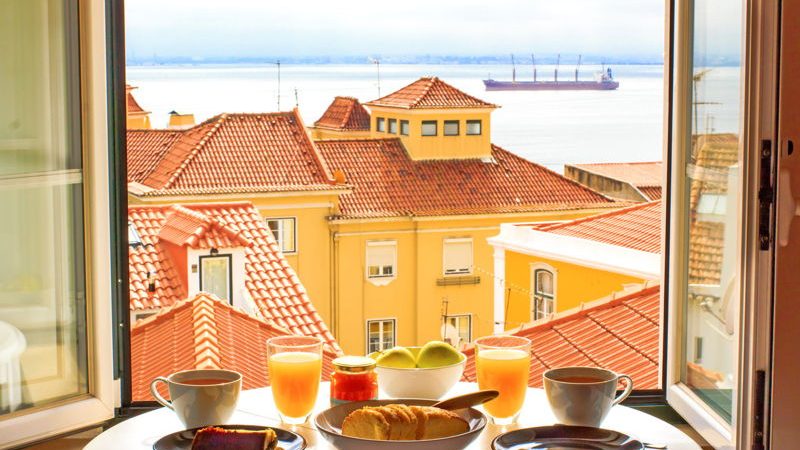 A table with breakfast of coffee and orange juice and view out across Algarve
