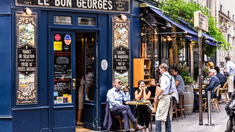 A blue Paris cafe with people sitting on outside tables