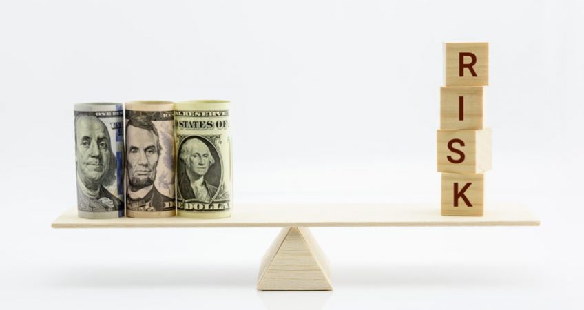 Money balanced on a scale opposite bricks that read risk