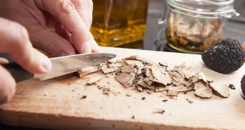 Hands cutting truffles with a knifle