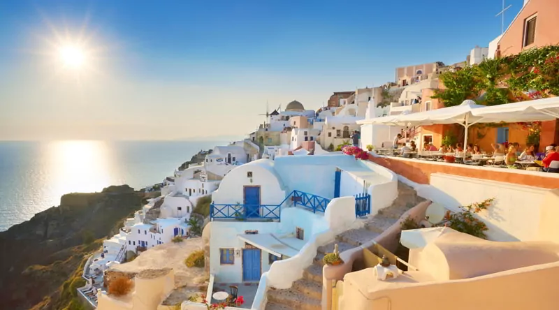 Afternoon view at Oia Town with sun in the background, Santorini Island, Cyclades, Greece.