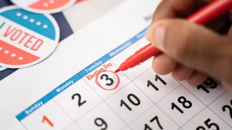 Close up of Hands marking November 3 election day on Calendar as reminder for voting.