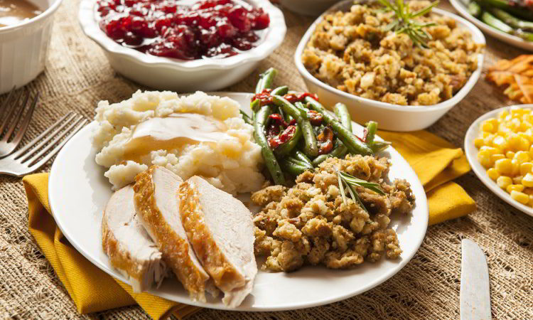 Homemade turkey Thanksgiving dinner with turkey, stuffing, mashed potatoes with gravy, green beans and cranberry sauce