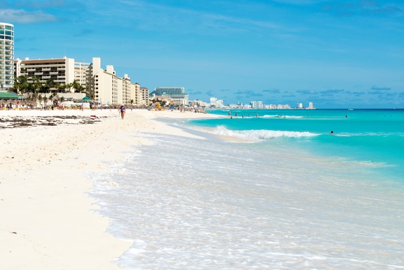 Tourists enjoy the sunny weather and relaxing on the beautiful beach in Cancun, Mexico.