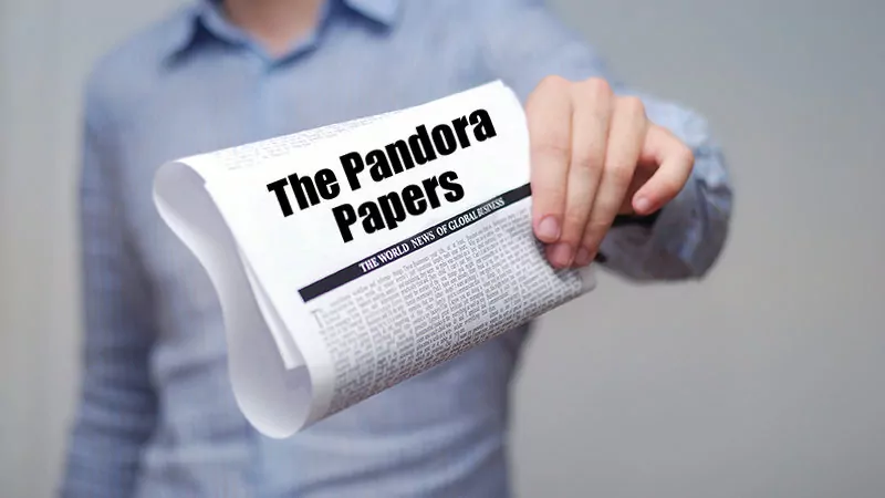 Man holding a newspaper with "The Pandora Papers" title