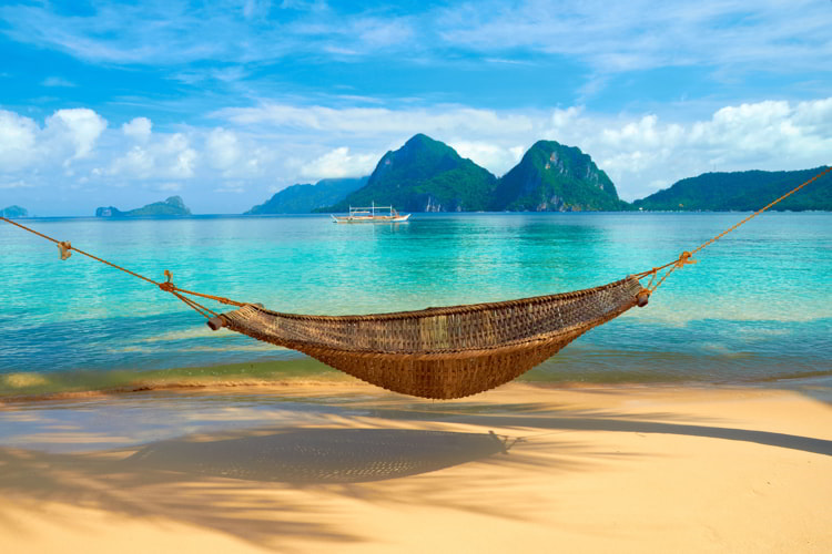 A hammock at the beach with the view of Bacuit Archipelago islands, Philippines