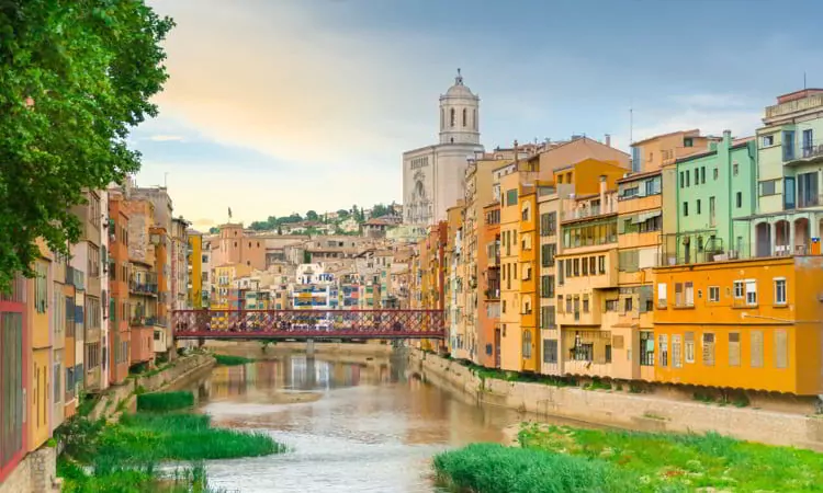 Girona colorful houses district, bridge, and Saint Mary Cathedral, buildings reflected in water in river Onyar. Catalonia Spain.