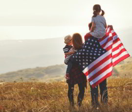 Happy family with American flag at sunset outdoors