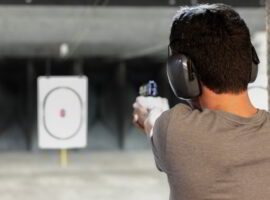 Man firing usp pistol at target in indoor shooting range