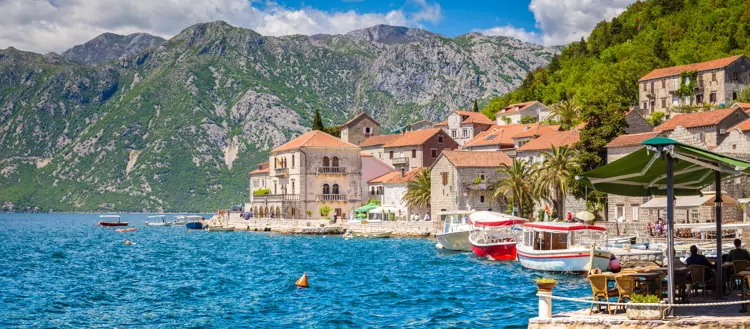 Scenic panorama view of the historic town of Perast at famous Bay of Kotor on a beautiful sunny day with blue sky and clouds in Summer, Montenegro