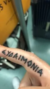 A tattoo on a finger that reads "Eudaimonia"