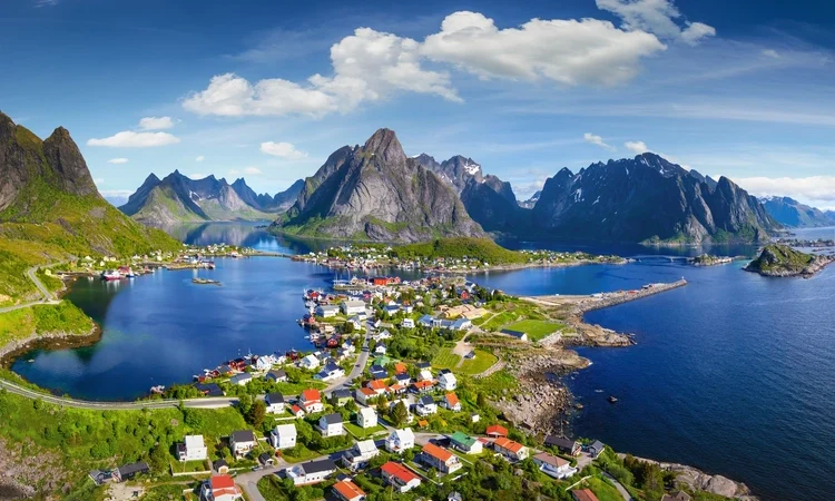 Reine, Lofoten, Norway. The village of Reine under a sunny, blue sky, with the typical rorbu houses.