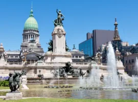 The Palace of the Argentine National Congress with fountains and statues in front, under a clear blue sky in Buenos Aires.