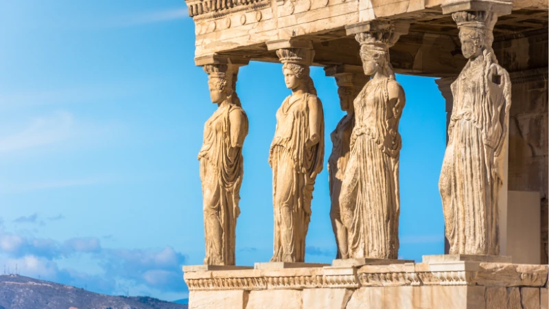The iconic Caryatid Porch of the Erechtheion on the Acropolis in Athens, Greece, representing the timeless heritage and appeal of living in the birthplace of democracy.